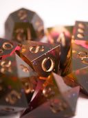 Ensemble de dés de jeux de rôle dégradés d'un orange chaud transparent vers un rose grenadine, vers un noir opaque brillant, aux chiffres peints couleur champagne, retro-sunset